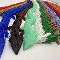 A collection of 3D-printed articulated dragon figurines arranged in parallel rows, showcasing different color options including rainbow, blue, brown, mint green, white, forest green, and others.