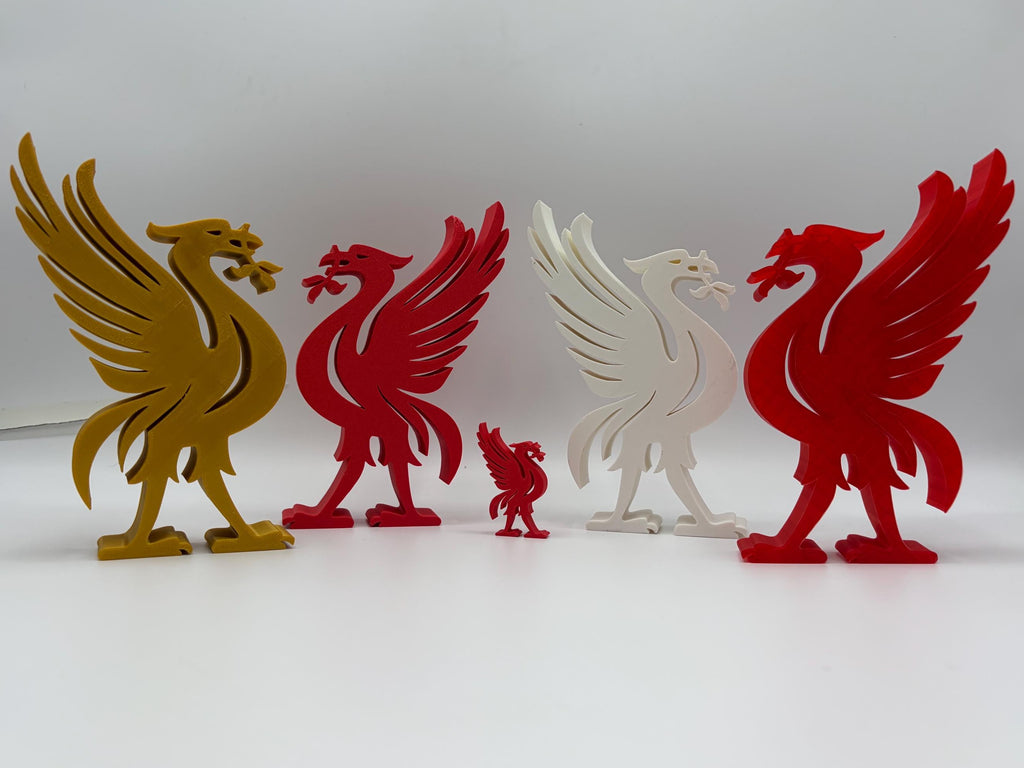 Five 3D printed Liverpool bird figurines in gold, red, and white, arranged on a white surface against a light gray background.
