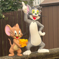 A Tom and Jerry figurine set featuring the classic cartoon characters Jerry the mouse and Tom the cat standing on a wooden fence outdoors.