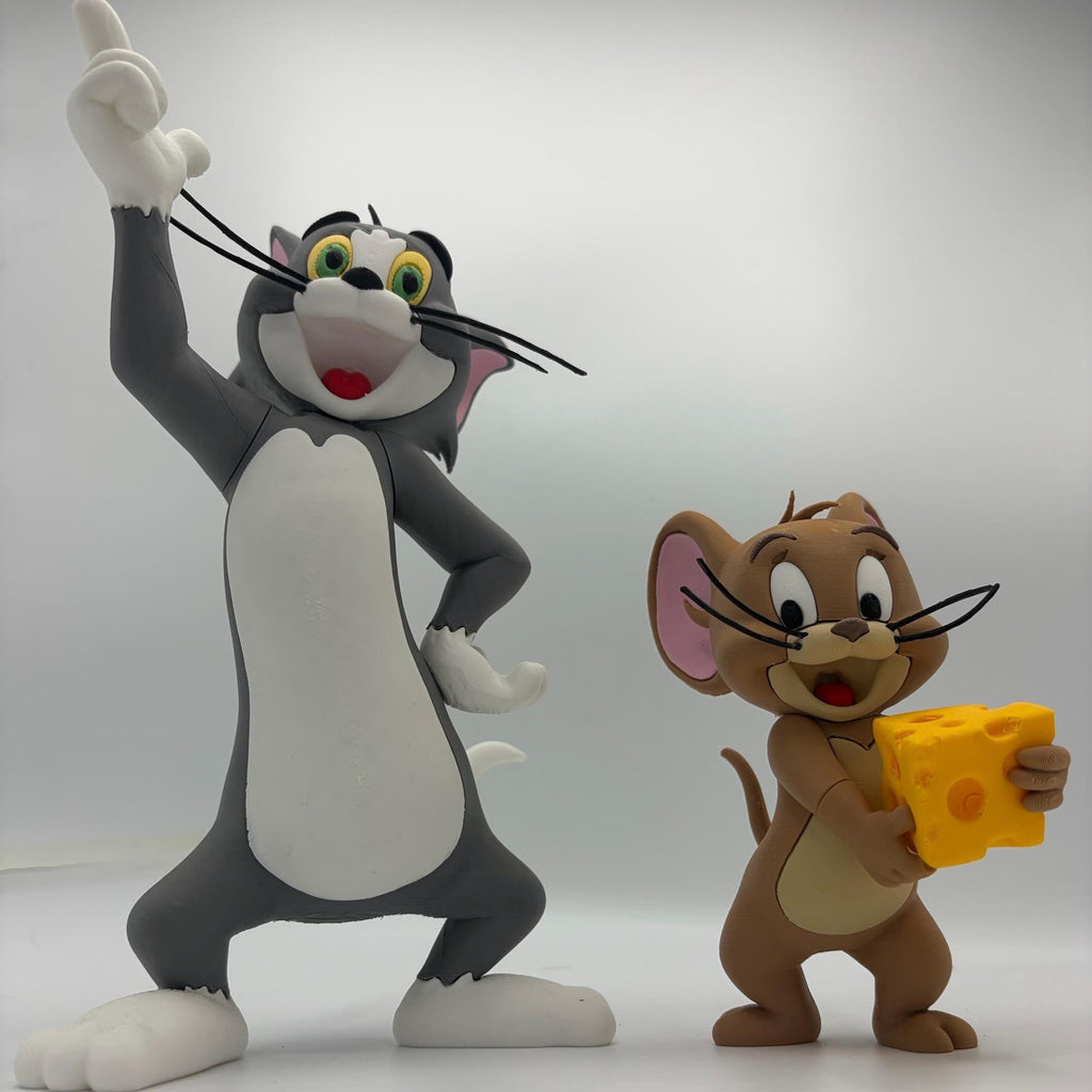 A Tom and Jerry figurine set featuring the grey and white cat Tom raising his paw, and the brown mouse Jerry holding a yellow cheese block, photographed against a light grey studio background.
