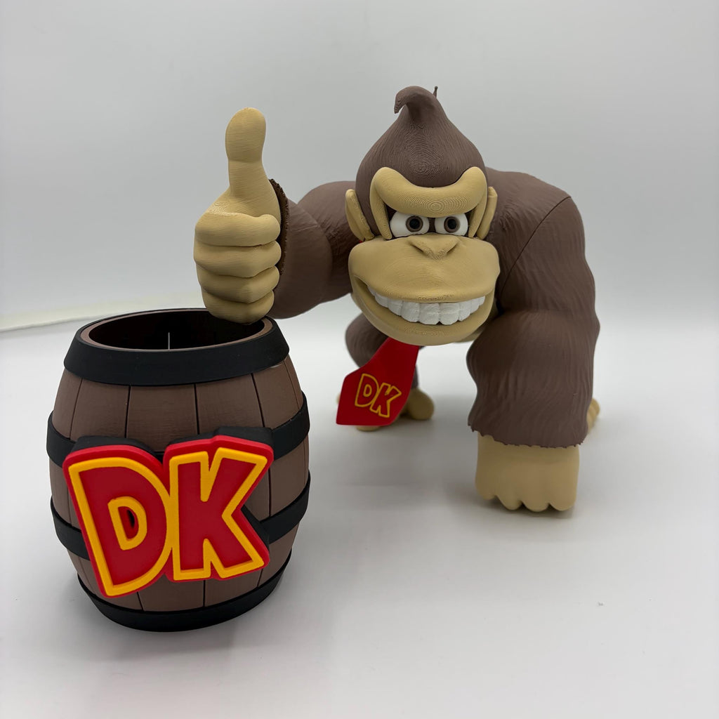 A Funko Donkey Kong collectible figure posed next to a matching barrel-shaped mug. The figure is brown with beige skin, wearing a red bandana with 'DK' written on it, and giving a thumbs-up.
