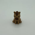 A small handmade crocheted-style pony figurine in light brown and dark brown, sitting on a plain light gray background.
