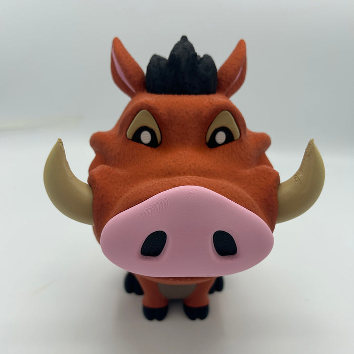 A stylized cartoon figurine of a warthog character, resembling Pumbaa from The Lion King, with orange-brown fur, a pink snout, beige horns, and a black mane, photographed against a plain light background.