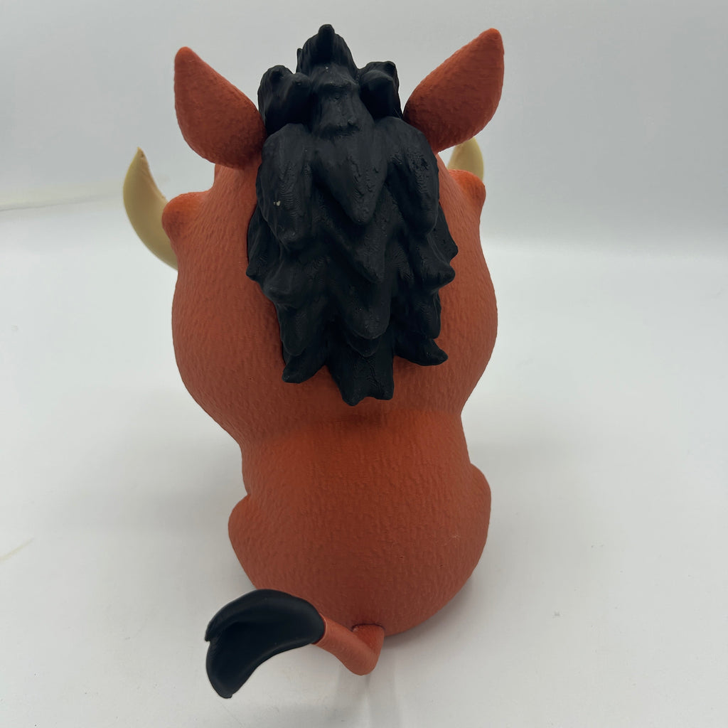 A small orange cartoon figurine shown from the back on a plain white studio background. The figure has brown ears, pale yellow horns, a black mane, and a black tail tip.