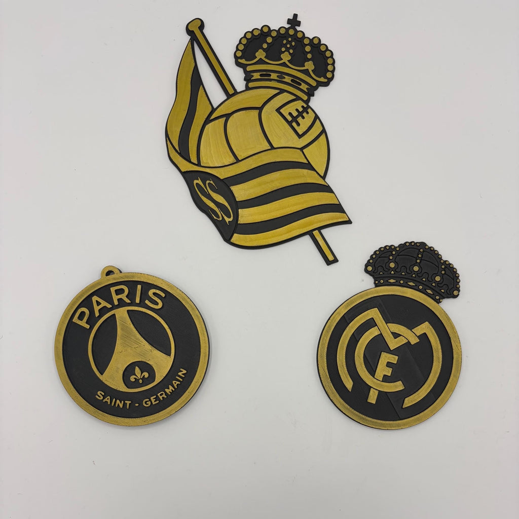 Three Paris Saint-Germain FC themed wall decals or stickers displayed on a white wall, featuring a large crest with a crown and flag, and two circular emblems.