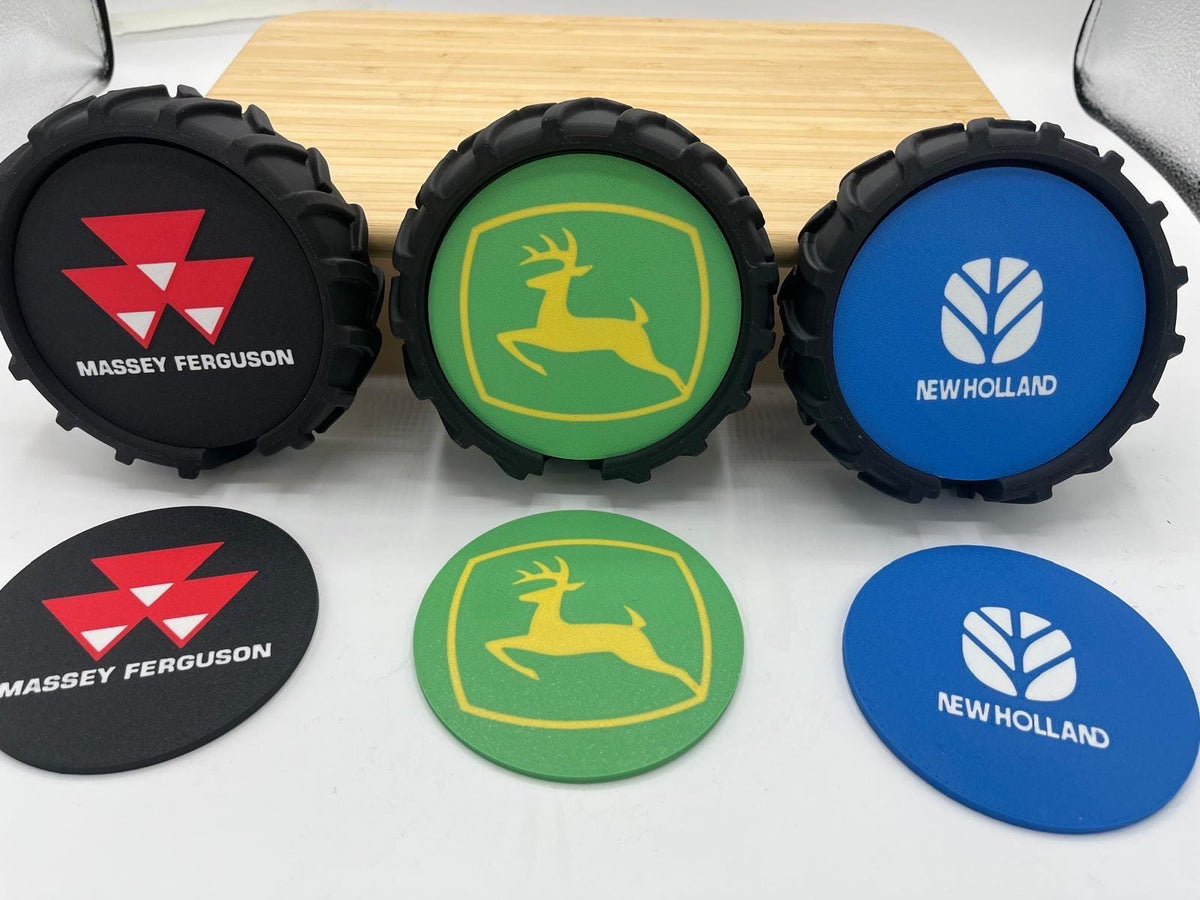 Six tractor-style tire-shaped coasters and matching round coasters displayed on a white surface, featuring Massey Ferguson and New Holland logos in black, green, and blue.